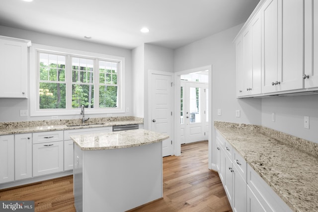 kitchen featuring light stone countertops, white cabinetry, sink, and light wood-type flooring