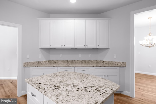 kitchen featuring white cabinetry, light hardwood / wood-style flooring, a notable chandelier, and decorative light fixtures