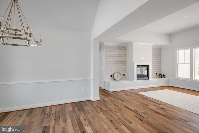 unfurnished living room featuring wood-type flooring, a chandelier, and vaulted ceiling