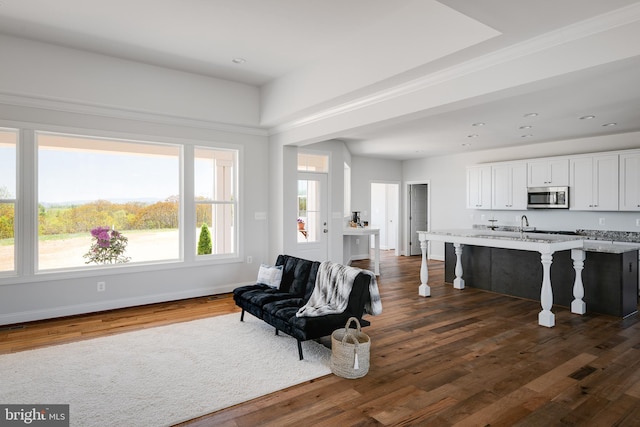 interior space with dark wood-type flooring, an island with sink, a kitchen breakfast bar, and white cabinets