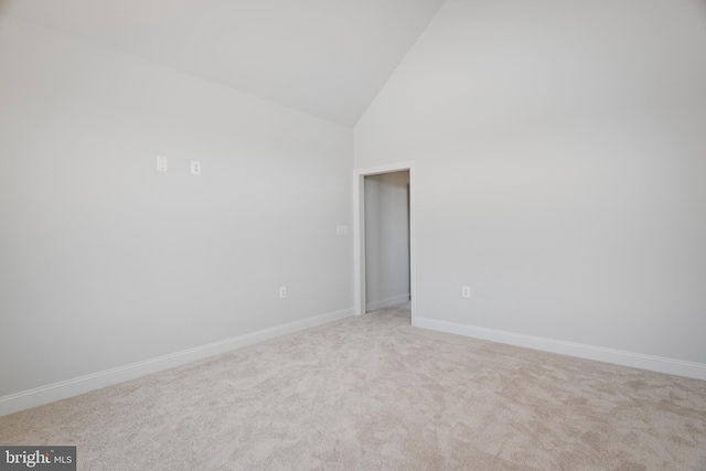 empty room featuring high vaulted ceiling and light carpet