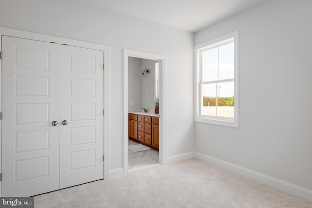 unfurnished bedroom featuring a closet, light colored carpet, and ensuite bathroom