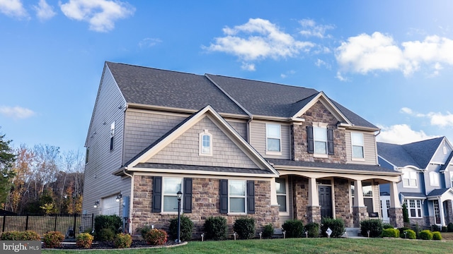 craftsman-style home featuring covered porch, a garage, and a front lawn