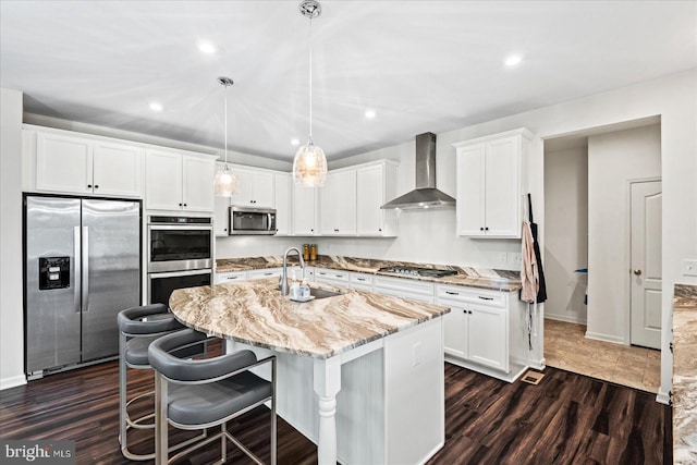 kitchen with sink, hanging light fixtures, stainless steel appliances, wall chimney range hood, and dark hardwood / wood-style flooring