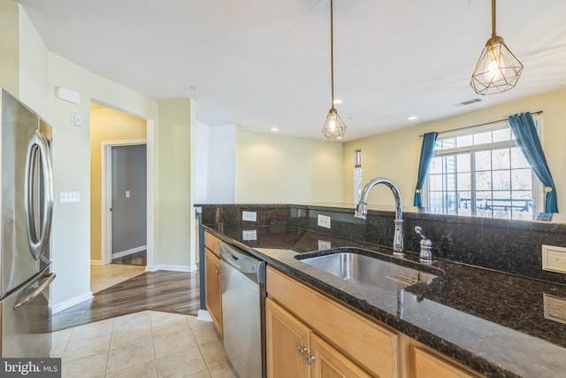 kitchen with dark stone countertops, sink, appliances with stainless steel finishes, and pendant lighting