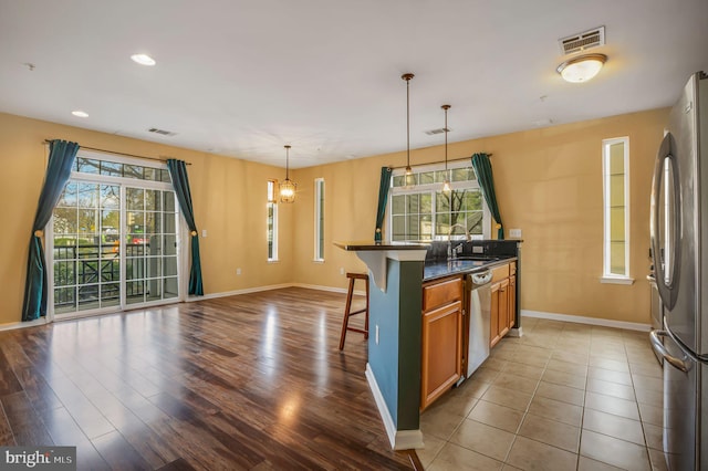 kitchen featuring a breakfast bar, wood-type flooring, stainless steel appliances, and a wealth of natural light