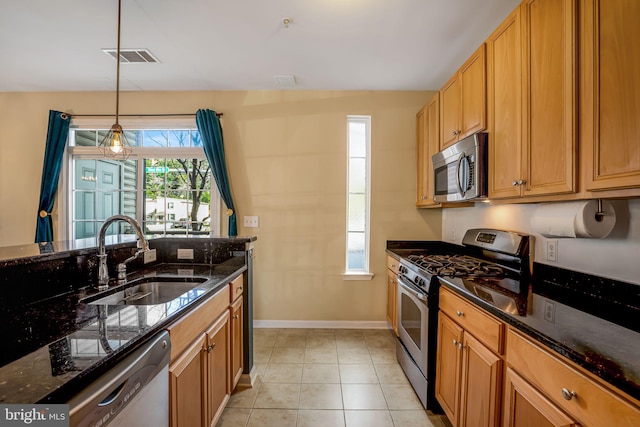 kitchen featuring hanging light fixtures, sink, appliances with stainless steel finishes, and dark stone counters