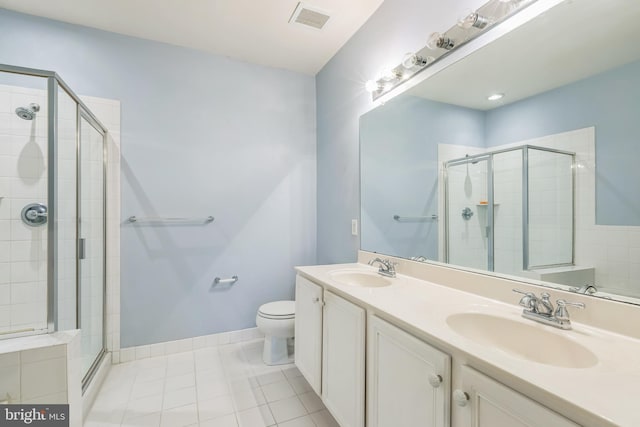 bathroom with tile patterned floors, vanity, a shower with shower door, and toilet