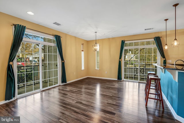 unfurnished dining area with a notable chandelier and dark wood-type flooring