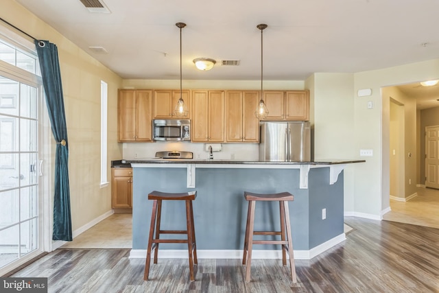 kitchen featuring a breakfast bar, appliances with stainless steel finishes, a center island, and hanging light fixtures