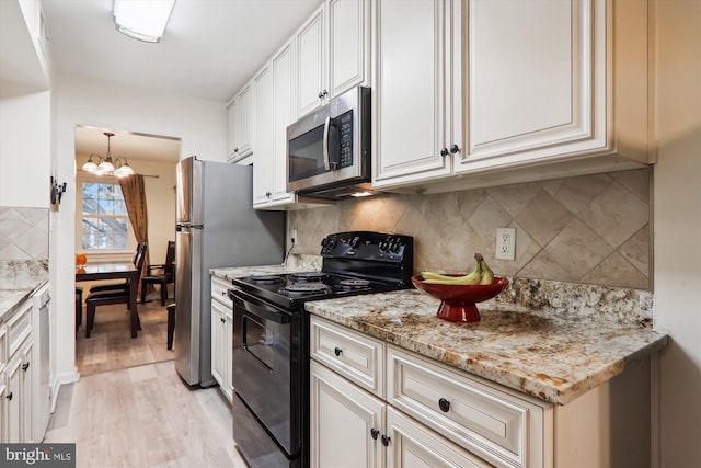 kitchen featuring white cabinetry, light stone countertops, stainless steel appliances, a notable chandelier, and light wood-type flooring