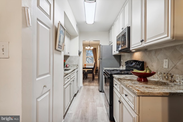 kitchen featuring electric range, white cabinetry, light stone counters, backsplash, and light wood-type flooring