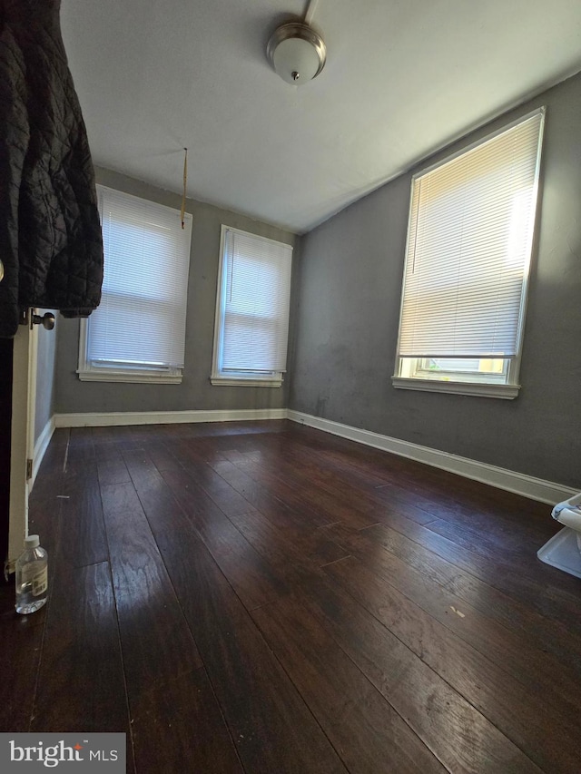 unfurnished room featuring plenty of natural light and dark wood-type flooring