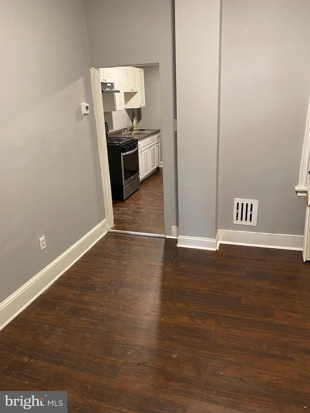 interior space featuring white cabinetry, sink, dark wood-type flooring, and stainless steel gas range