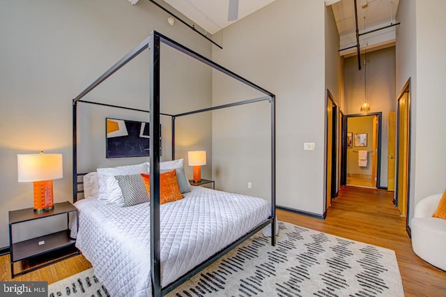 bedroom featuring a high ceiling and light hardwood / wood-style floors