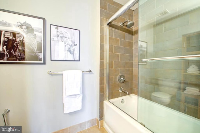 bathroom featuring toilet, bath / shower combo with glass door, and tile patterned floors