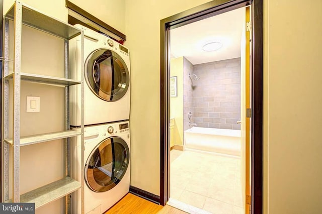 washroom with stacked washing maching and dryer and light hardwood / wood-style floors