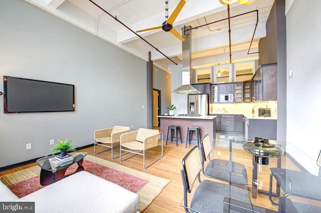 living room with rail lighting, light hardwood / wood-style floors, and a towering ceiling