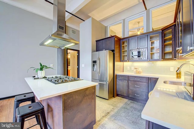 kitchen with appliances with stainless steel finishes, a kitchen bar, beam ceiling, backsplash, and island exhaust hood