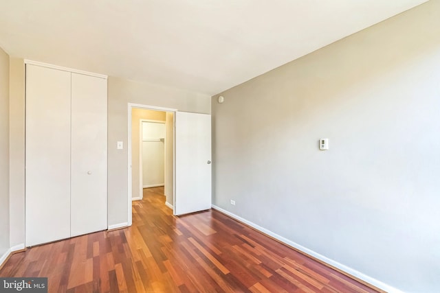 unfurnished bedroom featuring a closet and dark wood-type flooring