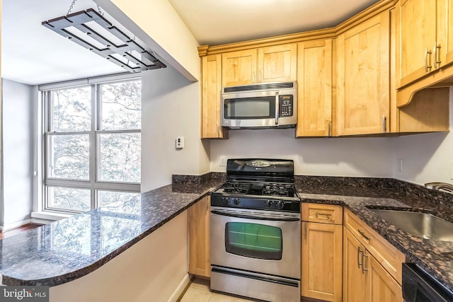 kitchen featuring sink, dark stone countertops, light tile patterned flooring, and stainless steel appliances