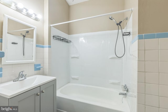 bathroom featuring tile walls, vanity, and tiled shower / bath