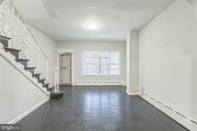 interior space with a baseboard heating unit and dark hardwood / wood-style flooring