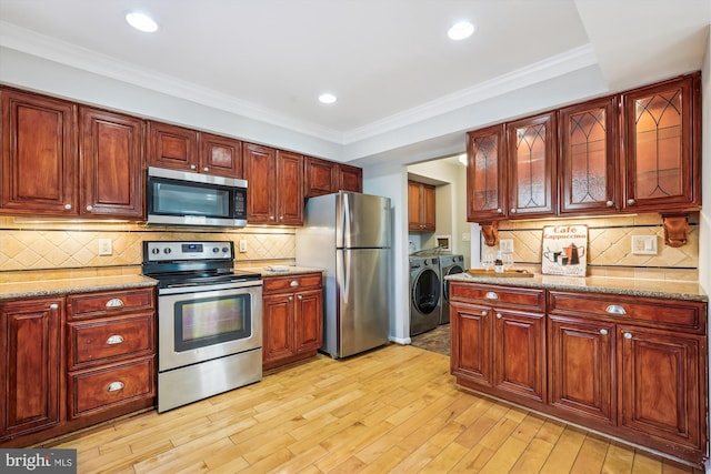 kitchen featuring stainless steel appliances, washer and dryer, light stone countertops, and tasteful backsplash