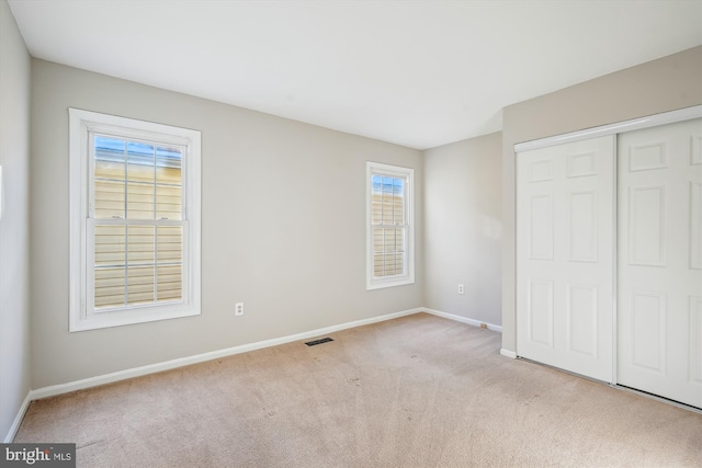 unfurnished bedroom with a closet and light carpet