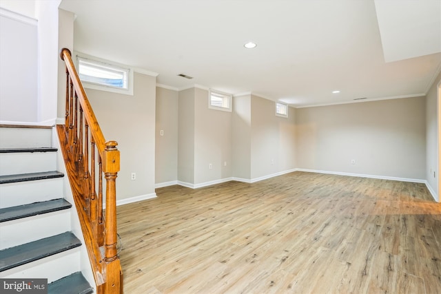 basement with light wood-type flooring, a healthy amount of sunlight, and ornamental molding