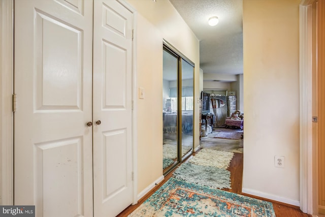 hall with a textured ceiling and light wood-type flooring