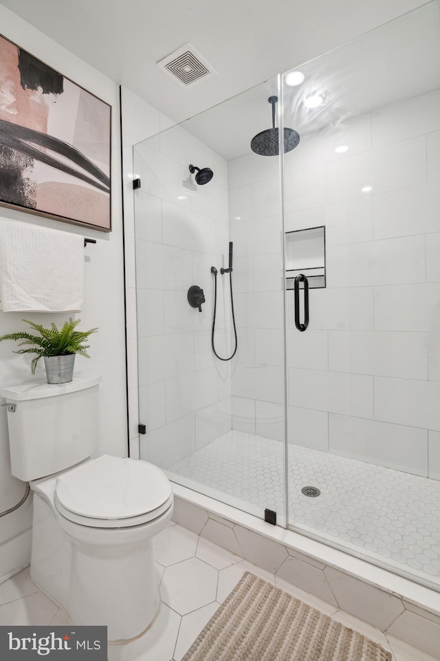 bathroom featuring toilet, tile patterned flooring, and a shower with shower door