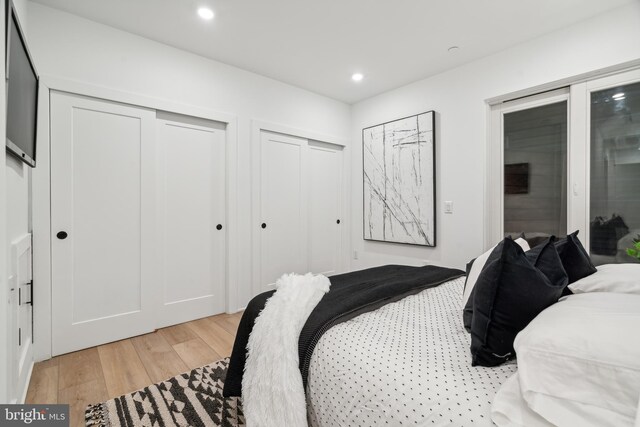 bedroom with light hardwood / wood-style flooring and two closets