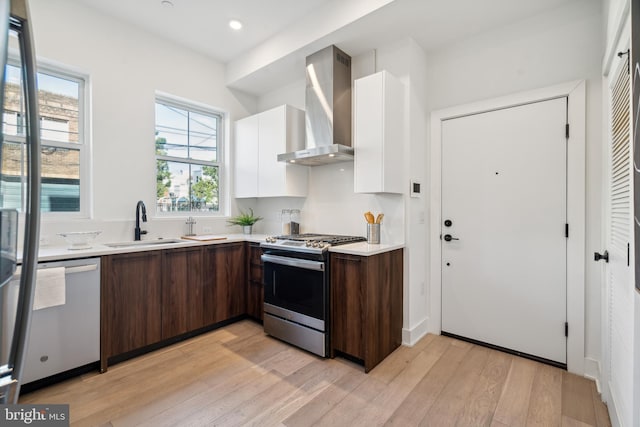 kitchen featuring white cabinetry, wall chimney range hood, dark brown cabinets, and stainless steel appliances