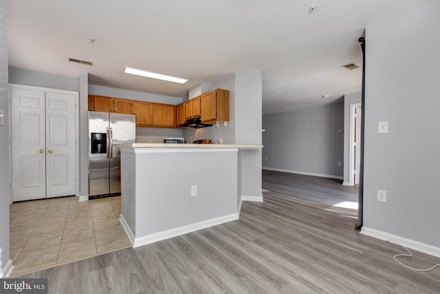 kitchen with light hardwood / wood-style floors and stainless steel fridge with ice dispenser