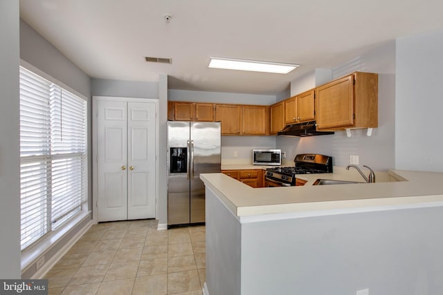 kitchen with kitchen peninsula, sink, light tile patterned floors, and stainless steel appliances