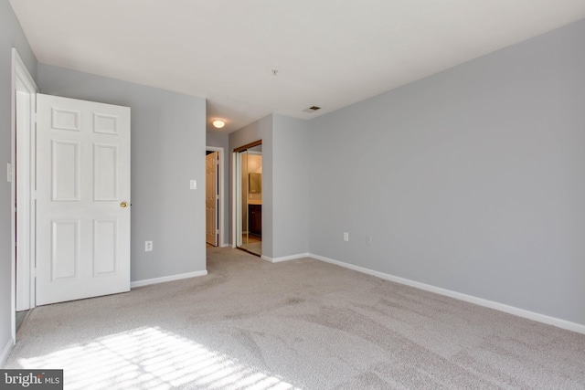 unfurnished bedroom featuring ensuite bath and light carpet