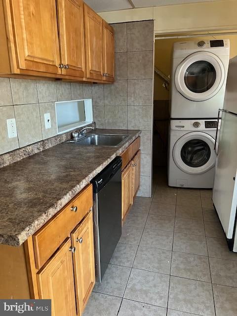 kitchen with black dishwasher, light tile patterned floors, sink, stacked washer / dryer, and white fridge