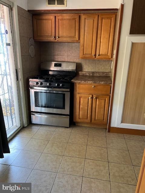 kitchen with a healthy amount of sunlight, light tile patterned floors, and stainless steel gas stove