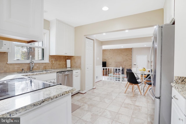 kitchen featuring white cabinets, light tile patterned floors, appliances with stainless steel finishes, backsplash, and light stone counters