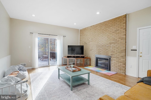 living room featuring light hardwood / wood-style flooring and a brick fireplace