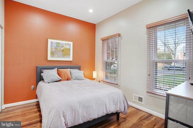 bedroom with multiple windows and hardwood / wood-style floors