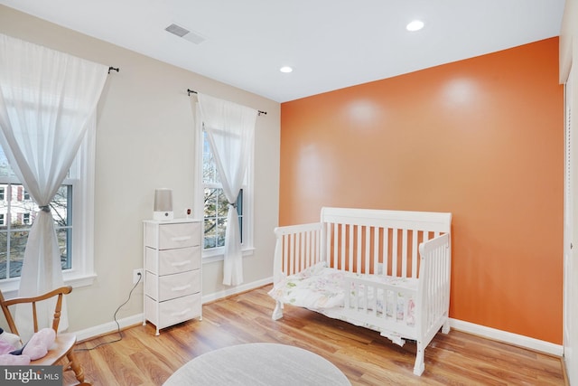 bedroom with wood-type flooring and a crib