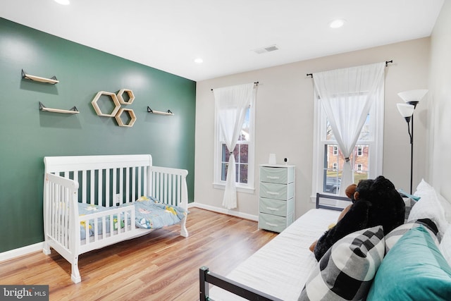 bedroom with a nursery area and hardwood / wood-style flooring