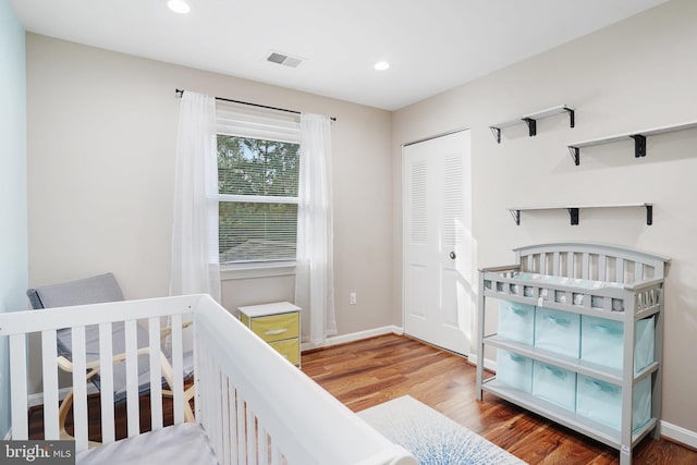 bedroom featuring a closet, a crib, and hardwood / wood-style flooring