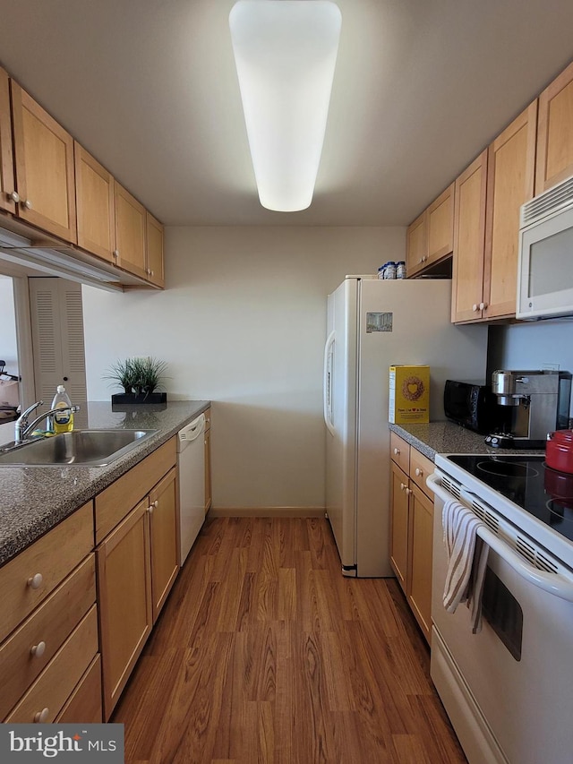 kitchen with hardwood / wood-style floors, white appliances, light brown cabinetry, and sink