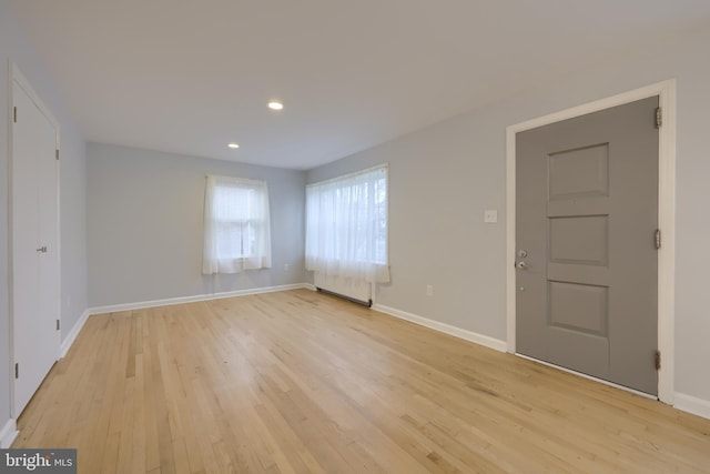 spare room with radiator heating unit and light hardwood / wood-style floors