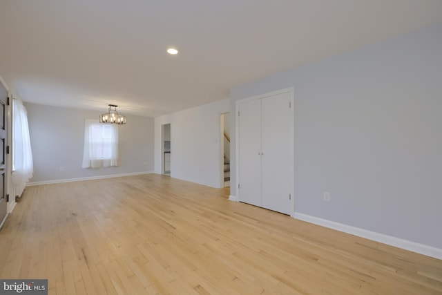 spare room with light hardwood / wood-style flooring and an inviting chandelier