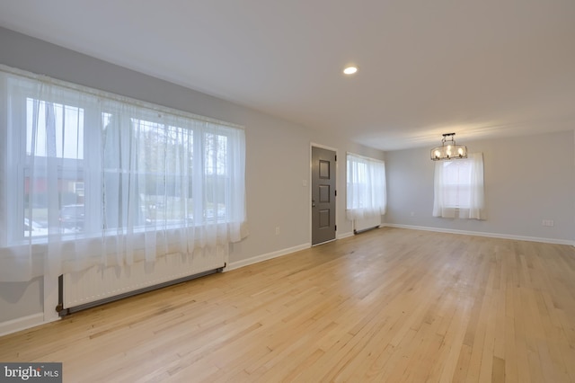 spare room with light hardwood / wood-style flooring and a notable chandelier