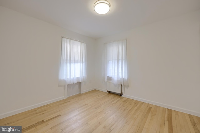 unfurnished room with radiator heating unit and light wood-type flooring